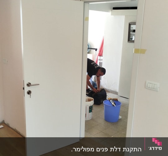דלת לבנה פתוחה עם ידית מתכת כסופה